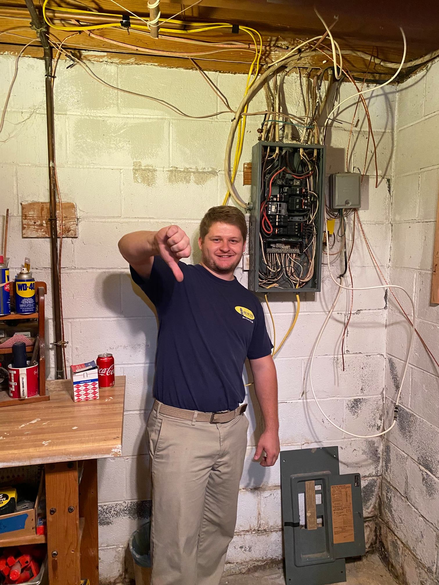 technician giving a thumbs down in front of electrical panel