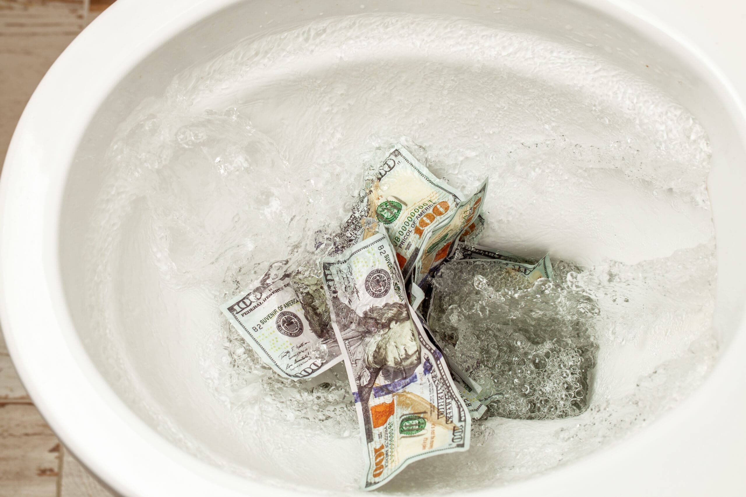Cash dollars are flushed into the toilet.