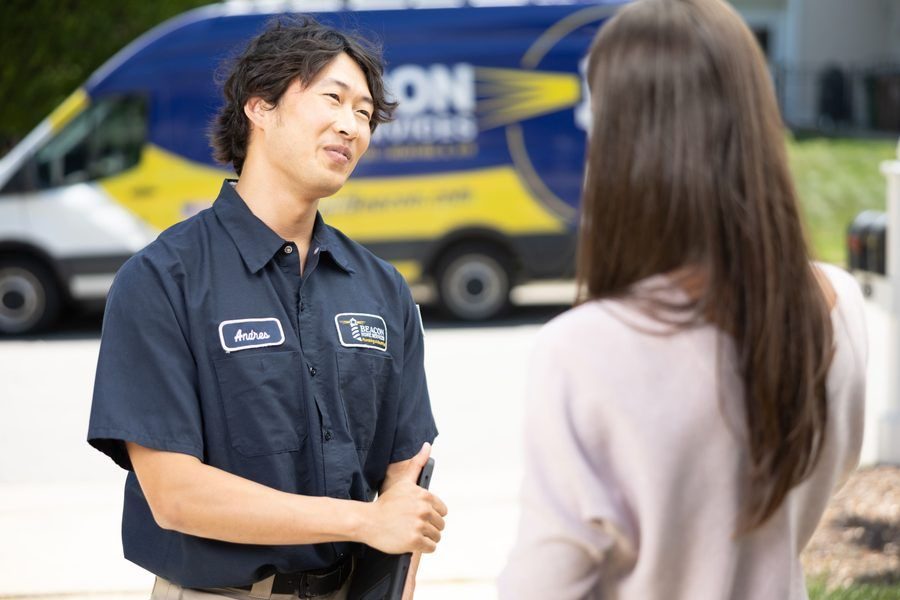 Service technician named Andres converses with a woman outdoors, a company van in the background.