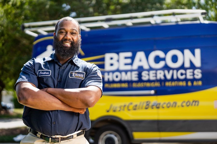 Bearded Beacon Home Services technician with arms crossed in front of the branded van behind him.